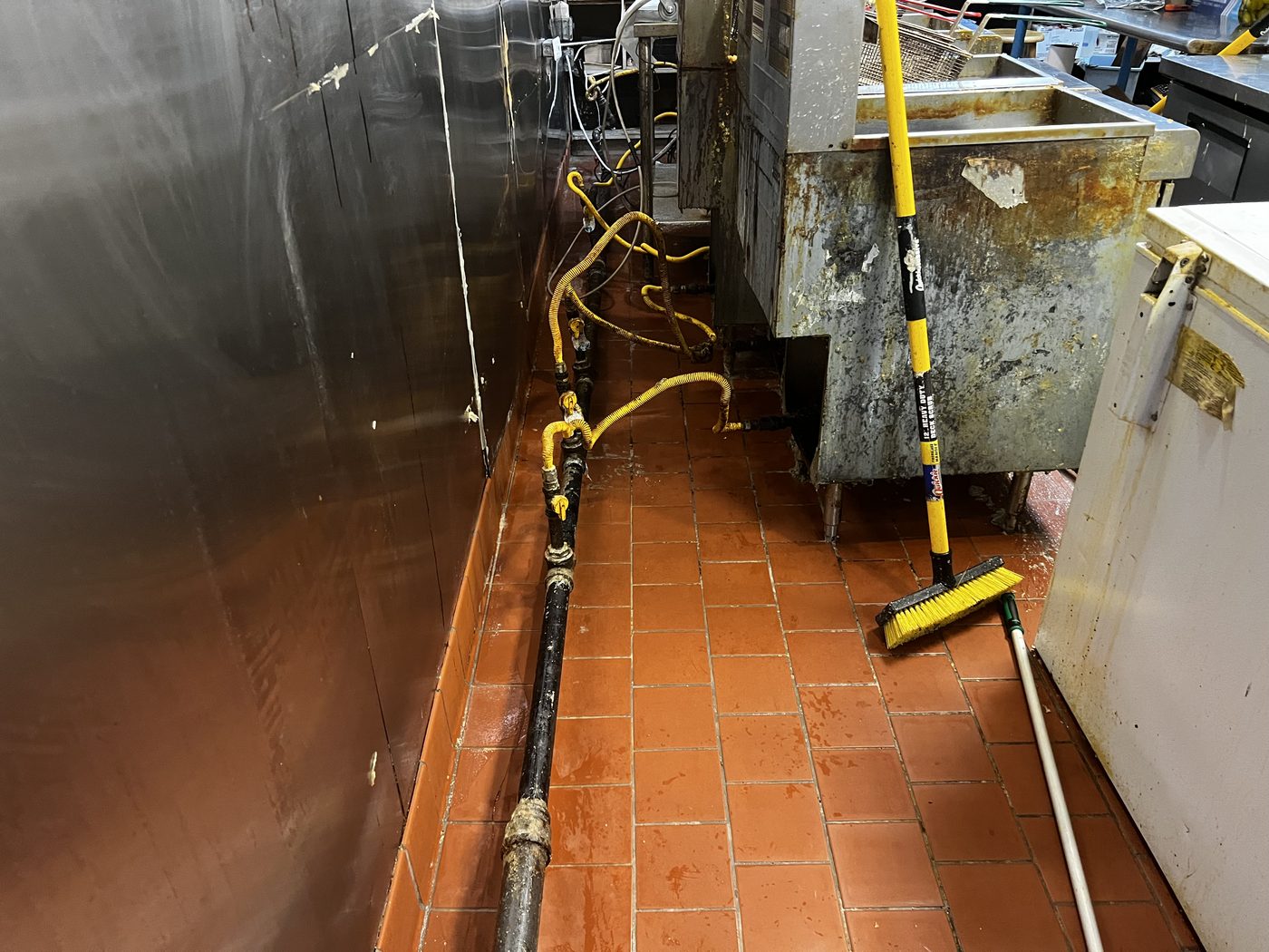 An E&L crew squeegeeing a commercial kitchen floor during a floor-care service