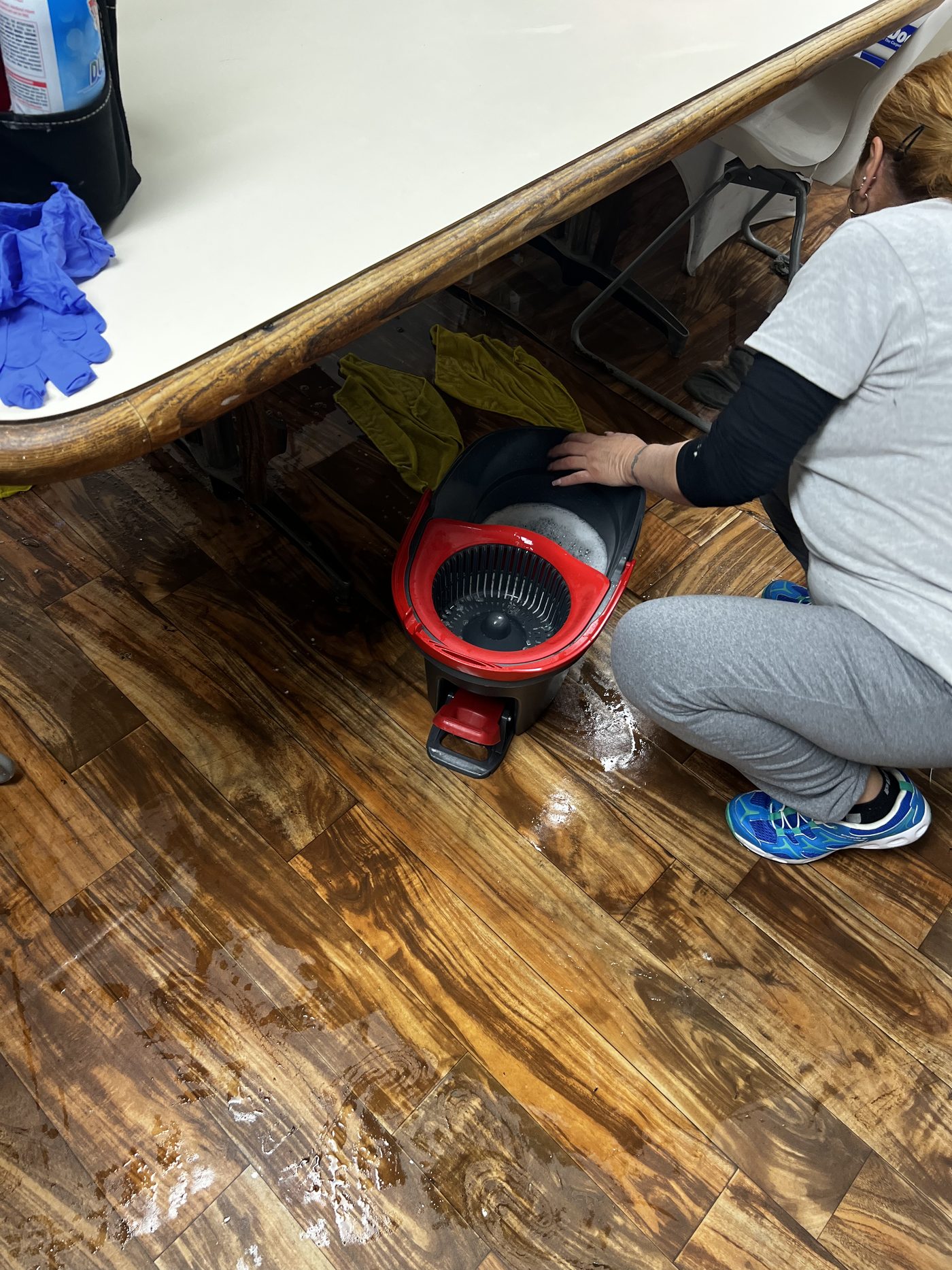 An E&L cleaner detailing beneath a counter with an air mover during a deep clean